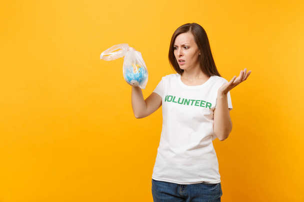 Жіночий портрет у білій футболці написаний напис "Зелений титул добровольця" тримається в поліетиленовій сумці Земляний світ глобус ізольований на жовтому тлі. Добровільна безкоштовна допомога, концепція благодійності
 - Фото, зображення