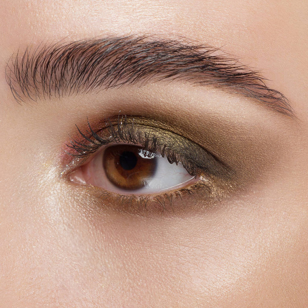 Krásný makro záběr ženského oka s klasickým make-upem. Dokonalý tvar obočí, hnědé stíny očí a dlouhé řasy. Kosmetika a make-up. Detailní makro záběr vzhledu módní vrstvy očí - Fotografie, Obrázek