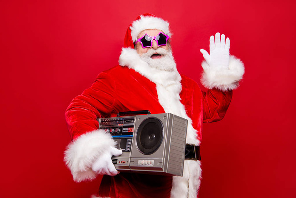 Profile side view aged funky white winter beard mature Santa modern star spectacles headwear costume hold audio record player make gesture hello goodbye isolated on December noel red background - Foto, Imagen