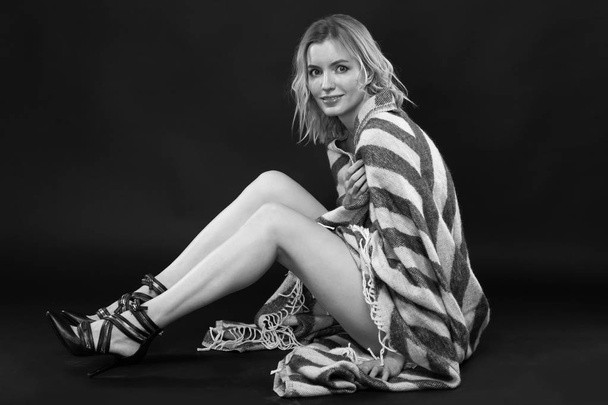 Beautiful sexy blond woman covers with a blanket on a dark background. Black and white photography. - 写真・画像
