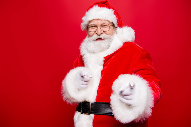 Are you ready to December event noel party? Glad happiness kind cheerful positive stylish Santa with white beard show forefinger in gloves on camera make beaming smile isolated vivid red background - Foto, afbeelding