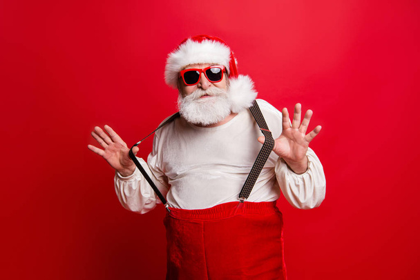 Portrait of cheerful positive dreamy funky Santa congratulations best wishes pulling suspenders ready to feast congrats isolated over bright vivid red background - Zdjęcie, obraz