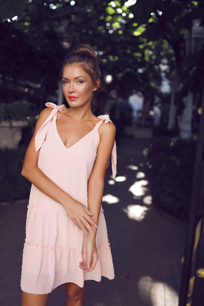 Tender girl wearing feminine pink dress,  makeup, style, hair bun, soft, light, fashion, clothes, party, event, outdoor, beautiful arms - Photo, Image