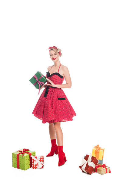 smiling young pin up woman standing near pile of gift boxes isolated on white - Foto, Imagem