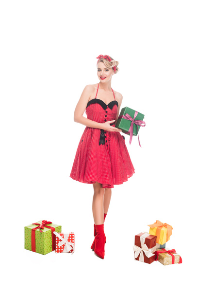 beautiful young pin up woman standing near pile of gift boxes isolated on white - Foto, imagen