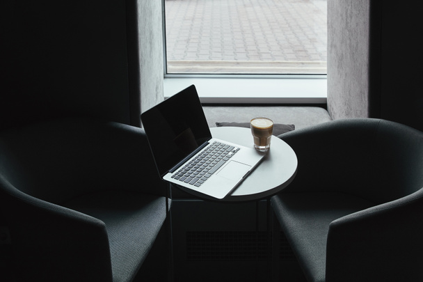 laptop with blank screen and cup of coffee on table in cafe    - Photo, Image