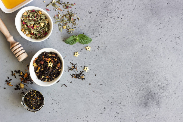 Black and green dried tea, mint leaves and honey on grey concrete background. Top view, copy space. - Foto, Bild