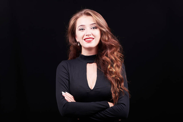 Studio portrait of a young elegant woman with bright make-up and curly hair on black background with copy space. - Fotó, kép