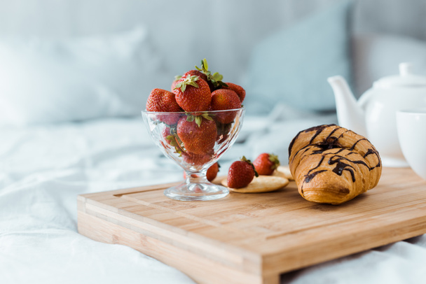 yummy breakfast of strawberries and croissant on wooden tray on bed - Φωτογραφία, εικόνα
