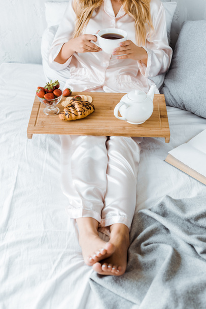 imagen recortada de la mujer en pijama desayunando en la cama por la mañana
 - Foto, Imagen