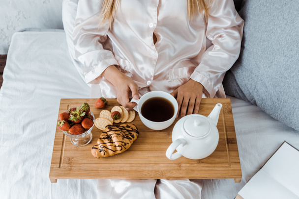 cropped image of woman in pajamas having breakfast in bed - Fotó, kép