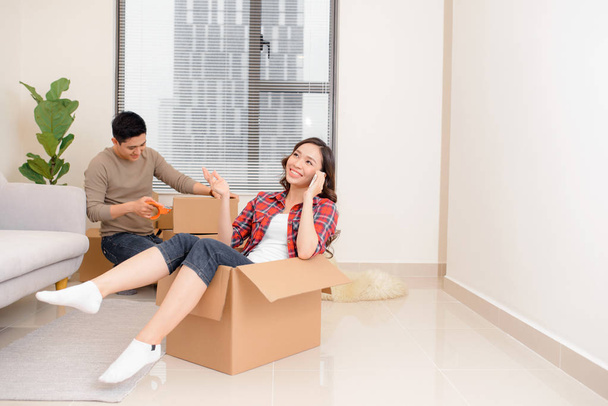 woman in the box, housewarming, the man is sitting on the couch, a new apartment - Photo, Image