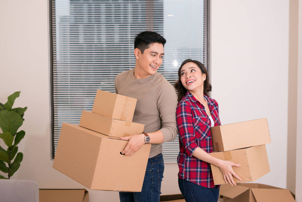 Couple heureux se regardant fixement et portant des boîtes dans leur nouvelle maison
 - Photo, image