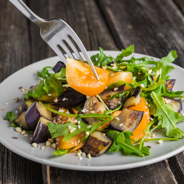 Warm salad with fried eggplant, arugula, orange tomatoes, , sesame seeds ,delicious healthy dinner, summer dish, diet food - Photo, image