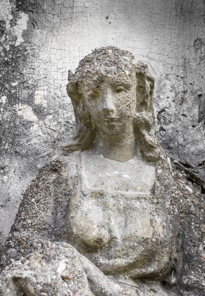 alte Statue einer Frau mit traurigem Gesichtsausdruck. Im Hintergrund eine graue und raue Wand. ideal für Konzepte und Hintergründe. - Foto, Bild