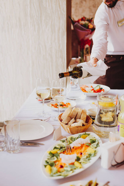 The waiter pours wine in a restaurant - Foto, imagen