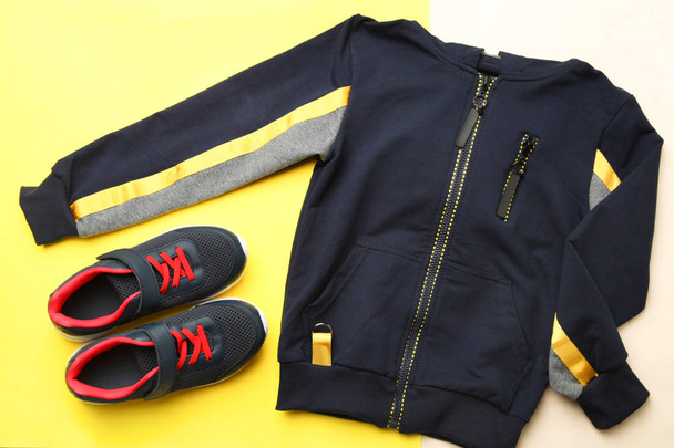 Чорний спортивний піджак і кросівки на жовтому бежевому фоні. Концепція спорту
. - Фото, зображення