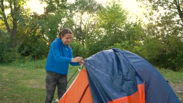 Femme met une tente touristique dans la forêt au coucher du soleil
 - Séquence, vidéo