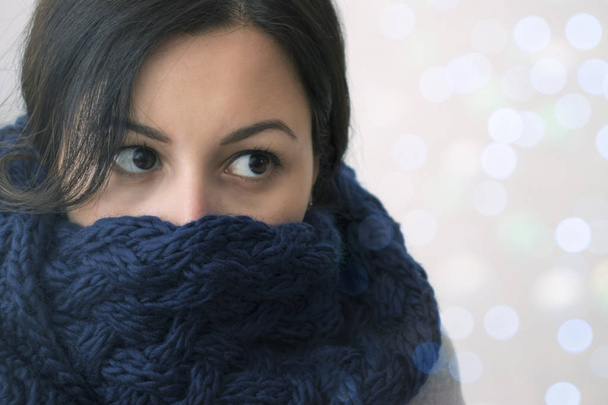 Χειμώνα πορτρέτο του μελαχρινή νεαρή γυναίκα που φοράει πλεκτό κασκόλ. - Φωτογραφία, εικόνα