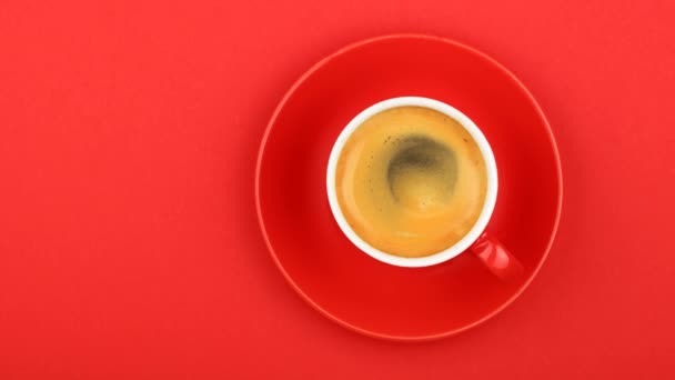 真上コーヒーの泡、昇格した平面図のスローモーション アニメーション cinemagraph スピンと鮮やかな赤い紙背景にエスプレッソ コーヒーとソーサーの 1 つ完全なコップを閉じる - 映像、動画