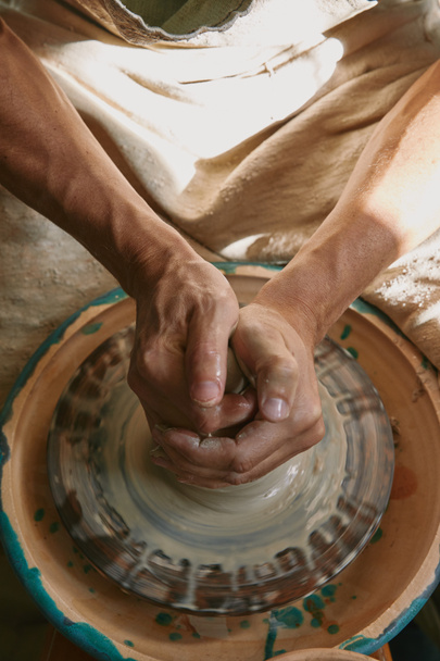 vista parcial del alfarero profesional trabajando en la rueda de cerámica en el taller
 - Foto, Imagen