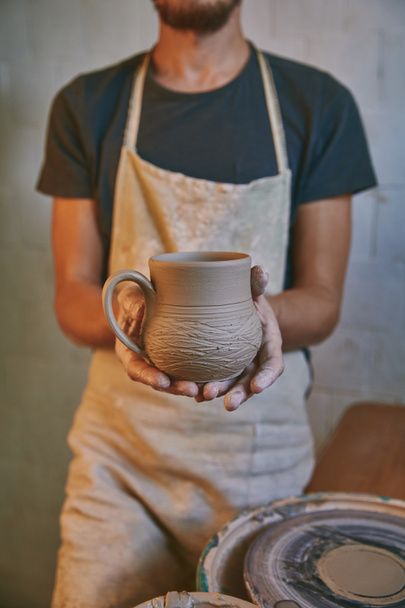 ワーク ショップで土鍋を持ってエプロンの陶工の画像をトリミング - 写真・画像