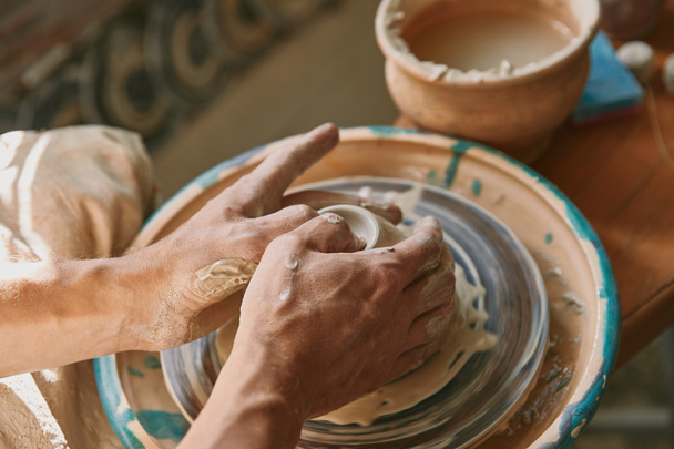 vista de cerca de las manos del hombre que trabajan en la rueda de cerámica en el taller
 - Foto, Imagen
