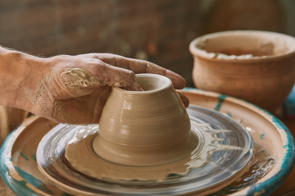 imagen recortada de alfarero profesional que trabaja en la rueda de cerámica en el taller
 - Foto, imagen