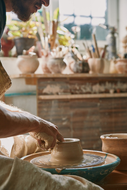 immagine ritagliata del vasaio maschio che lavora sulla ruota della ceramica in officina
 - Foto, immagini