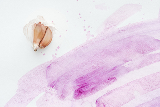 top view of raw garlic on white surface with pink watercolor strokes and blots - Photo, Image
