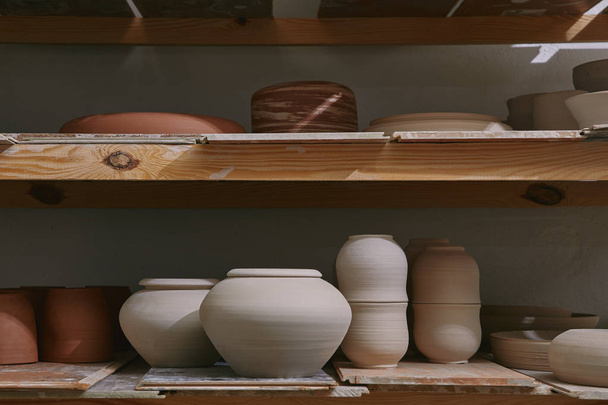 ceramic bowls and dishes on wooden shelves at pottery studio - Photo, Image