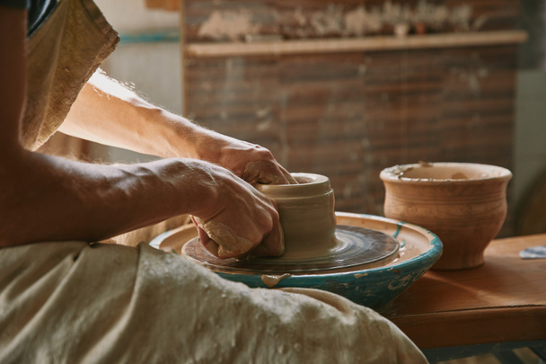 partial view of professional potter working on pottery wheel at workshop - Photo, Image