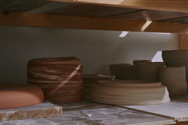 ceramic bowls and dishes on wooden shelves at pottery studio - Foto, Imagen