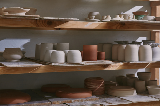 ceramiczne misy i naczynia na drewniane półki w pracowni ceramiki - Zdjęcie, obraz