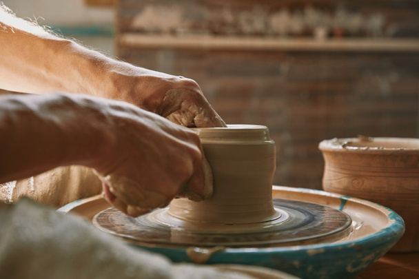 vue rapprochée des mains de l'homme travaillant sur la roue de poterie à l'atelier
 - Photo, image