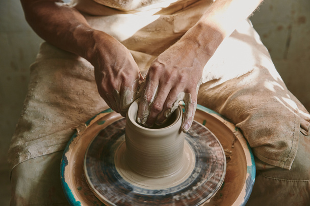 Close-up van mannelijke potter handen werken op aardewerk wiel op workshop - Foto, afbeelding