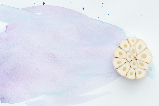 felülnézet fűszeres nyers fokhagyma, fehér felületen lila akvarell vonásokkal - Fotó, kép