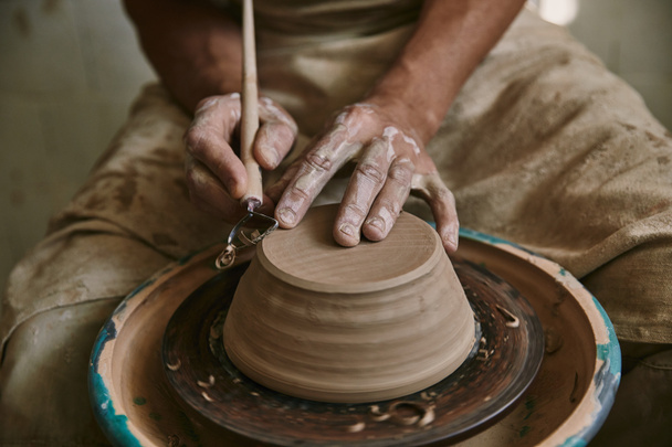 imagen recortada de alfarero profesional decorando olla de arcilla en el taller
 - Foto, Imagen