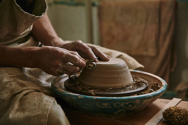 selective focus of professional potter decorating clay pot at workshop - Photo, Image