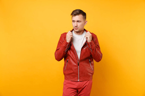 Portrait vogue confident handsome young man 25-30 years in red leather jacket, t-shirt stand isolated on bright trending yellow background. People sincere emotions lifestyle concept. Advertising area - Photo, Image