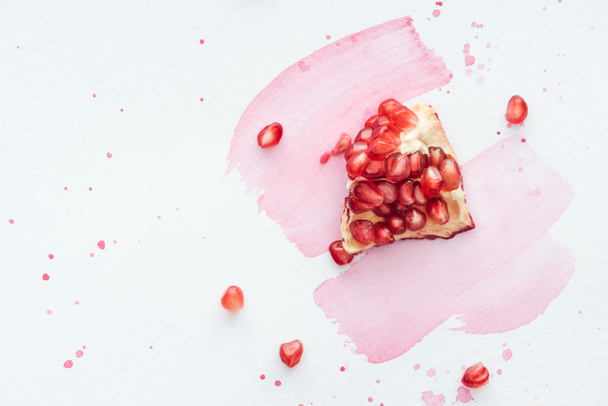 top view of pomegranate on white surface with pink watercolor strokes - 写真・画像