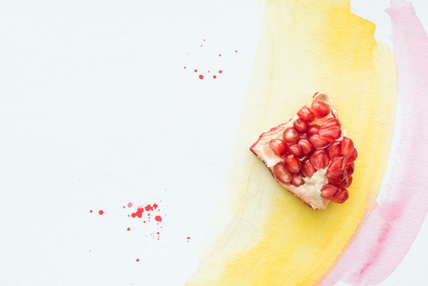 top view of delicious pomegranate piece on white surface with yellow and pink watercolor strokes - Photo, Image