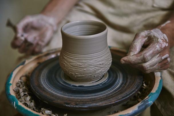 imagen recortada del artesano masculino que trabaja en la rueda de alfarero en el taller
 - Foto, Imagen