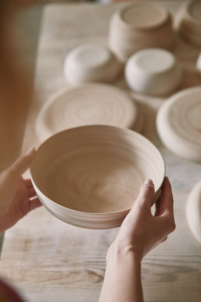 selective focus of woman holding ceramic dish at pottery studio - Photo, Image