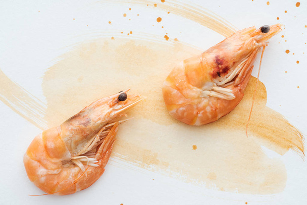 top view of uncooked shrimps on white tabletop with watercolor strokes - Foto, Bild