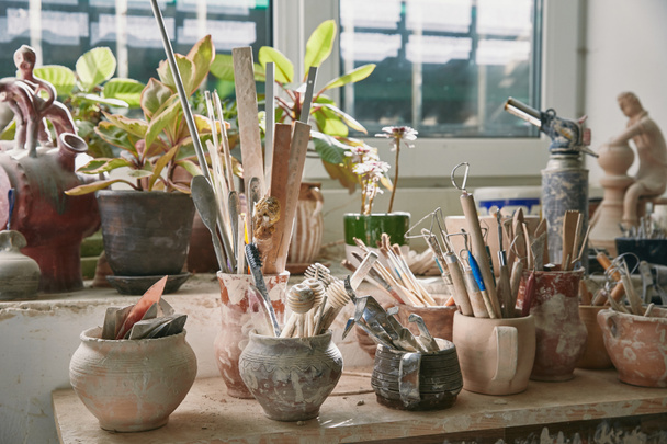 foco seletivo de ferramentas de cerâmica e pincéis à mesa no estúdio de cerâmica
 - Foto, Imagem