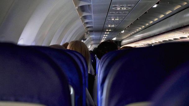 Candid shot between seats of passengers sitting inside airplane while traveling - Photo, Image