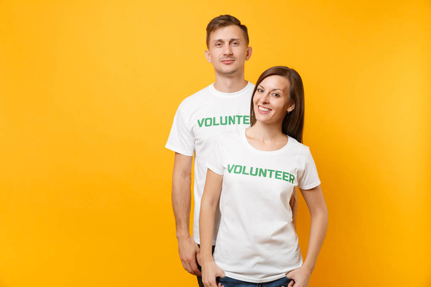 Muotokuva nuorista kollegoista pari valkoisessa t-paidassa kirjallisella kirjoituksella vihreä otsikko vapaaehtoinen eristetty keltaisella taustalla. Vapaaehtoinen vapaa työ, apu apu, hyväntekeväisyys armon tiimityö käsite
 - Valokuva, kuva
