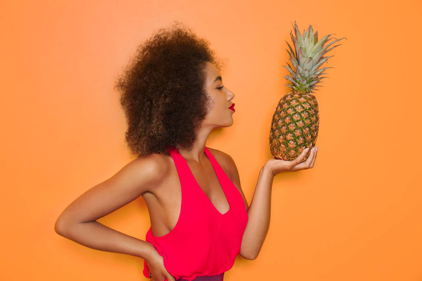 Прекрасна афро-американська жінка з ананасом на кольоровому фоні - Фото, зображення