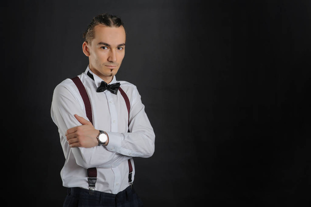 Young handsome boy in white shirt with bowtie, clock on hand, clouse vie - Foto, afbeelding